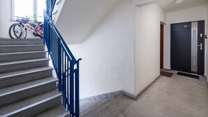 A staircase with blue railings leading to a landing. A bicycle is parked against the wall near a window. - Bemowo Lazurowa Chic Apartment (Warszawa)