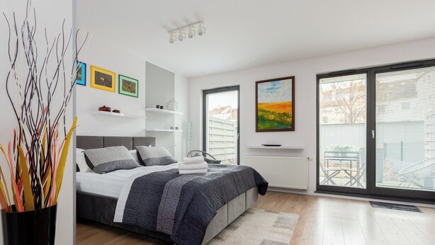 Ein modernes Schlafzimmer mit einem Bett, einem Nachttisch, einem Sessel, einem Fenster und Kunstwerken an den Wänden.