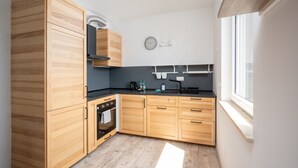 Une cuisine moderne avec des meubles en bois, un four encastré et une fenêtre qui laisse entrer la lumière naturelle.