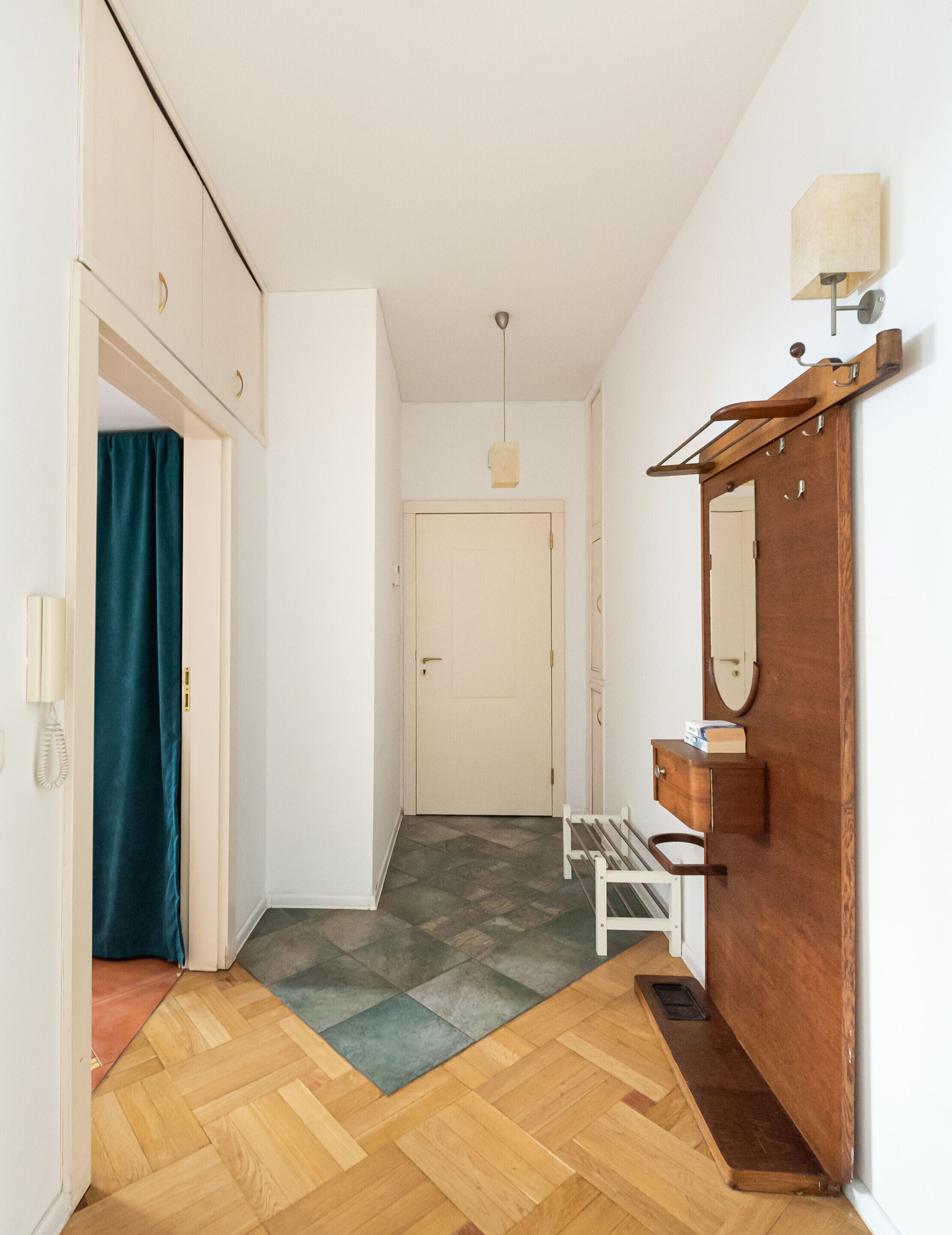 A hallway with a wooden bench, a door, and a mirror on the wall.