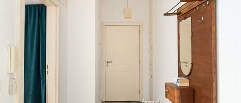 A hallway with a wooden bench, a door, and a mirror on the wall.