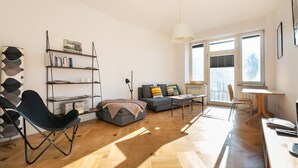 Ein modernes Wohnzimmer mit einer Couch, einem Couchtisch, einem Bücherregal und einem Essbereich mit Tisch und Stühlen.