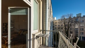 Eine moderne Wohnung mit Balkon, großen Fenstern und Blick auf benachbarte Gebäude.