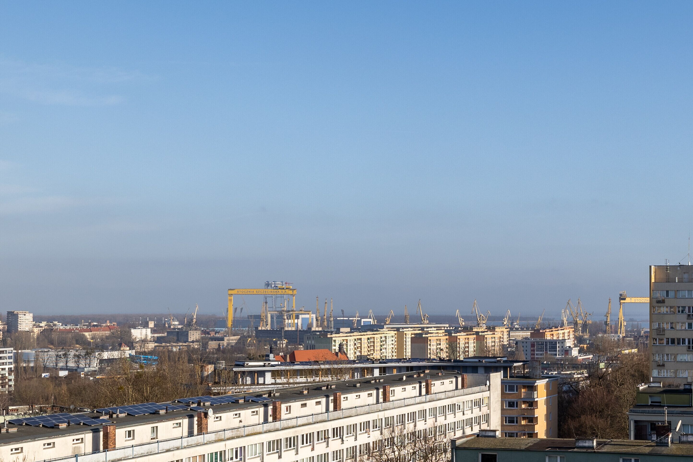 Eine Stadtansicht mit Industriegebäuden, Kränen und Wohngebieten.