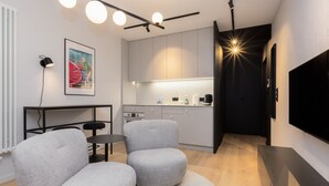 A modern living room with grey upholstered chairs, a round rug, a small table, and a flat-screen TV mounted on the wall. - Quercus Deluxe Studio #B (Gdansk)