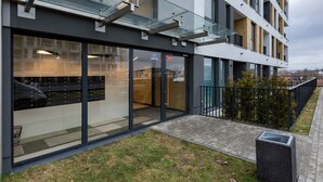A modern building with large glass windows, a visible entrance, and a paved walkway. - Quercus Deluxe Studio #B (Gdansk)