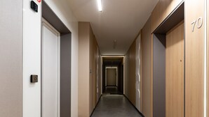 A modern hotel corridor with wooden flooring, a central vent, and a number '70' on the wall. - Quercus Deluxe Studio #B (Gdansk)