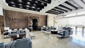A modern lounge area with a stone wall, comfortable seating, and a view of the city. - Beautiful 3 bedroom/3 bathroom Condo In Las Palomas Beach & Golf Resort (Puerto Penasco)