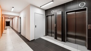 Un hall d’entrée moderne doté de trois ascenseurs, de carrelages blancs et d’un design épuré et minimaliste.