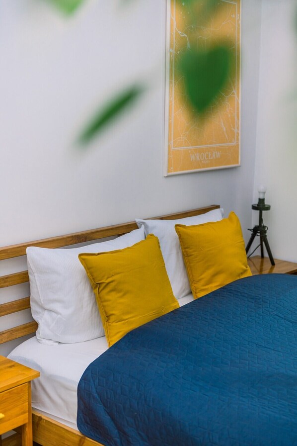A bedroom with a wooden headboard, a bed with a blue quilt, and two mustard-colored pillows.