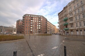 A paved square with a modern building and a historic building with balconies.