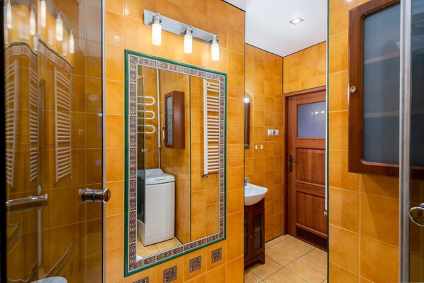 A bathroom with a large mirror, a sink, and a shower area.