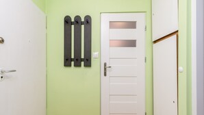 A hallway with a white door, a light green wall, and a door with a frosted glass panel. - Krowoderskich Zuchów Standard Studio (Kraków)