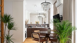 A modern kitchen with a dining area, featuring a wooden floor, a dining table with chairs, and a chandelier. - Hoża Modern Apartment (Warszawa)