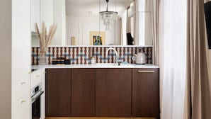 A modern kitchen with a wooden cabinet, a white countertop, a sink, and a kettle. - Hoża Modern Apartment (Warszawa)