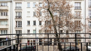 A multi-story building with balconies, a tree in the foreground, and cars on the street. - Hoża Modern Apartment (Warszawa)