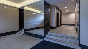 A modern hotel lobby with a staircase leading to upper floors, a reception desk, and a clean, minimalist design.