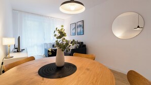 Un comedor moderno con una mesa redonda de madera, un florero con plantas y una lámpara colgante.