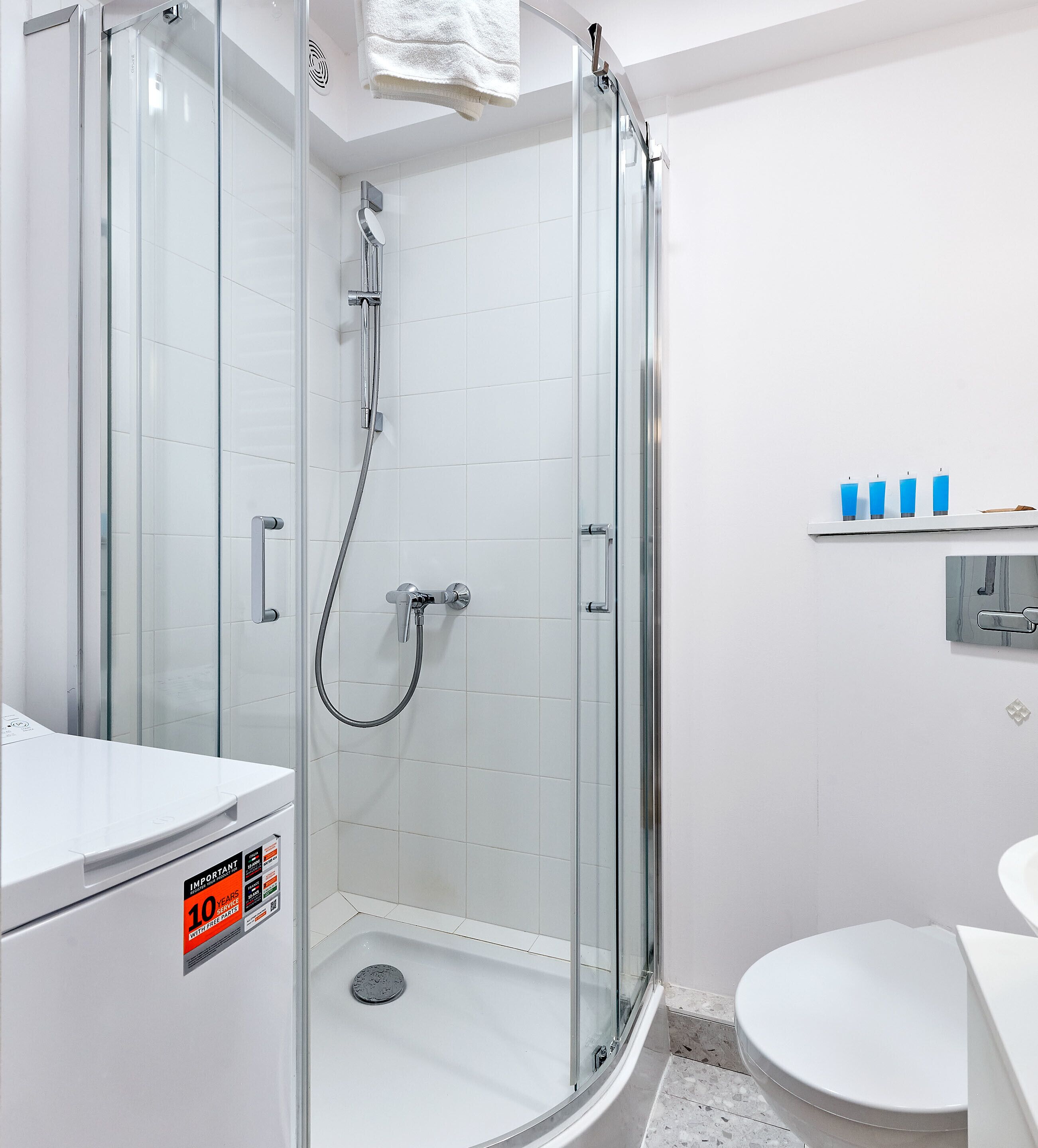 Une salle de bain moderne avec une douche à parois de verre, des toilettes blanches et un lavabo.