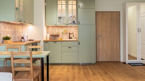 Une cuisine moderne avec des meubles de couleur vert clair, une table à manger en bois et un plancher en bois.