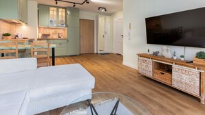 Un salon moderne avec un grand téléviseur à écran plat, une table basse en verre et un canapé.