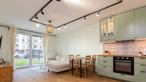 Une cuisine moderne avec un coin repas, comprenant une table en bois, des chaises et un four encastré.