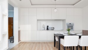 Eine moderne Küche mit weißen Schränken, einem Esstisch mit Stühlen und einem eingebauten Backofen.