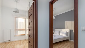 Ein Schlafzimmer mit Holzboden, einem Bett, einem Fenster mit Jalousien und einer weißen Heizung.