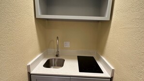A compact kitchen with a sink, stove, and two cabinets. - Royal Inn (Kenedy)