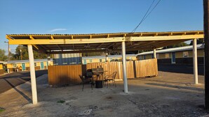 A covered outdoor area with a barbecue grill, chairs, and a table. - Royal Inn (Kenedy)