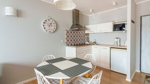 A compact kitchen with a tiled backsplash, a built-in microwave, and white cabinetry.