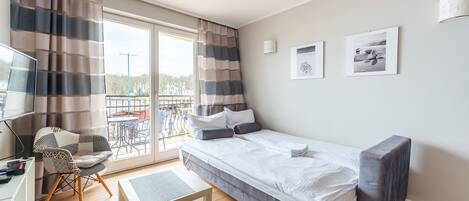 Una habitación de hotel moderna con cama, escritorio, silla y balcón con vistas.
