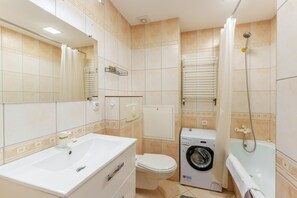 Un baño con lavamanos, inodoro, lavadora y bañera.