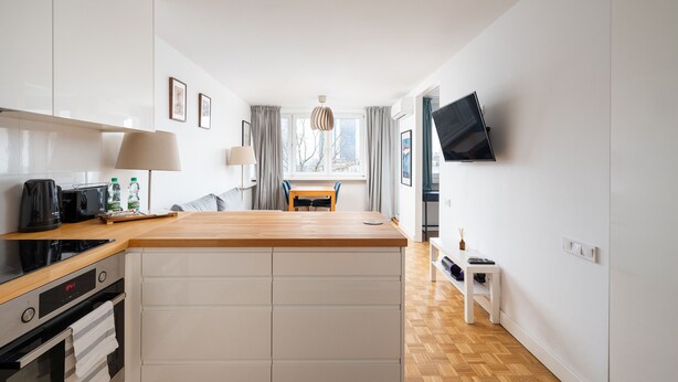 A modern kitchen with a wooden countertop, built-in oven, and a dining area with a table and chairs. - Plac Zawiszy Cosy Apartment (Warszawa)