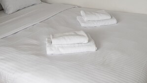 A neatly made bed with white linens and pillows, and two folded towels on the bed. - Plac Zawiszy Cosy Apartment (Warszawa)