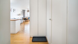 A hallway with a kitchen area, a dining table with chairs, and a door. - Plac Zawiszy Cosy Apartment (Warszawa)