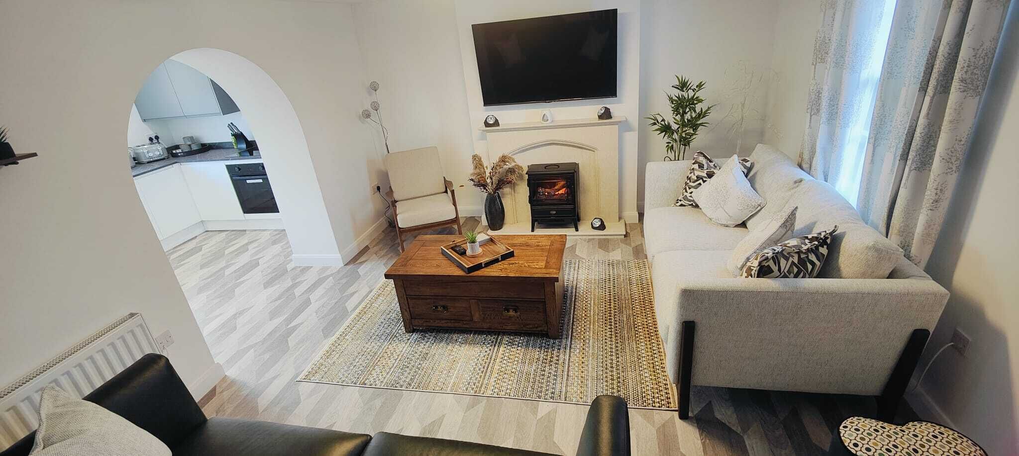 A modern living room with a sofa, coffee table, fireplace, and a TV mounted on the wall.