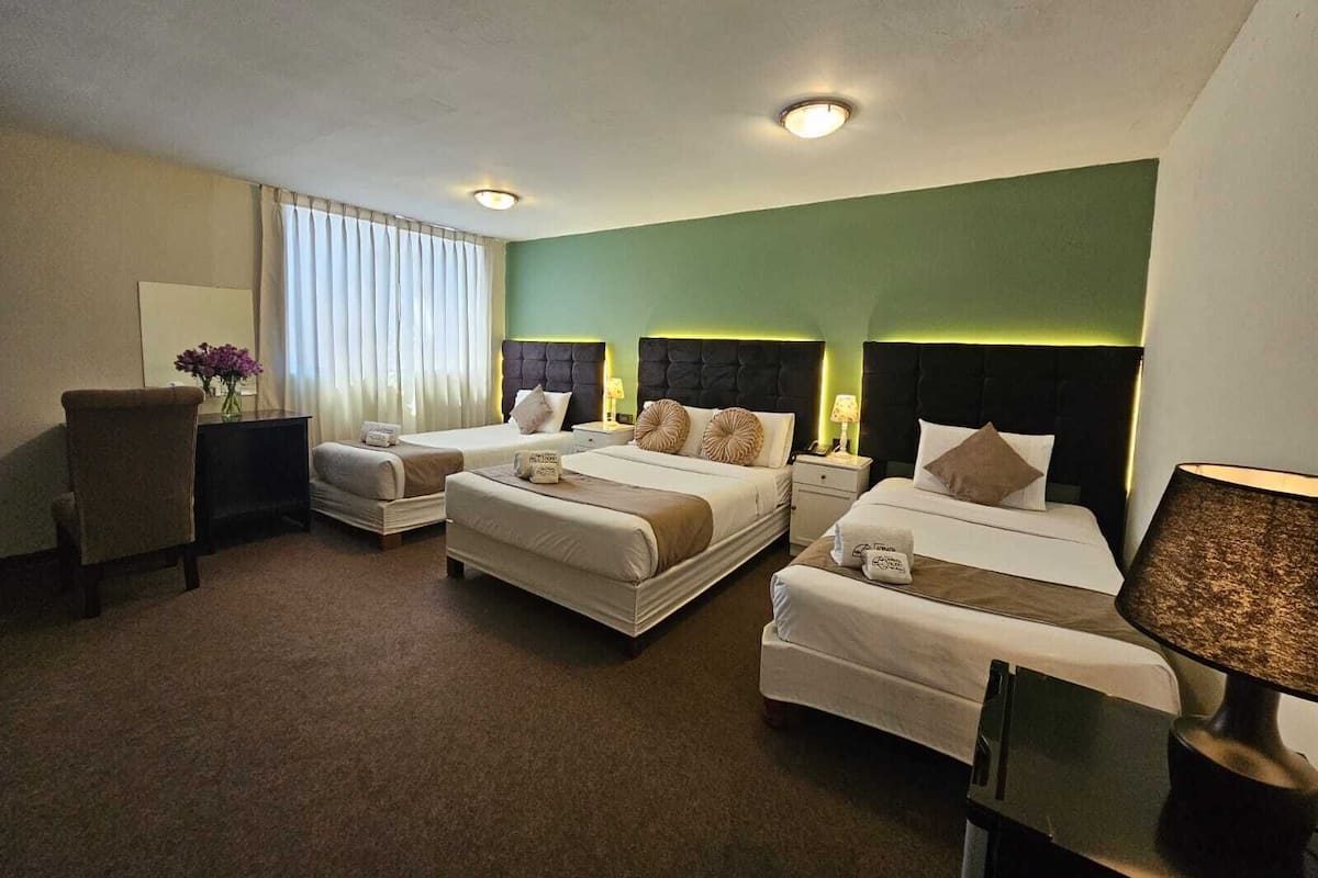 A hotel room with two beds, a desk, and a chair.