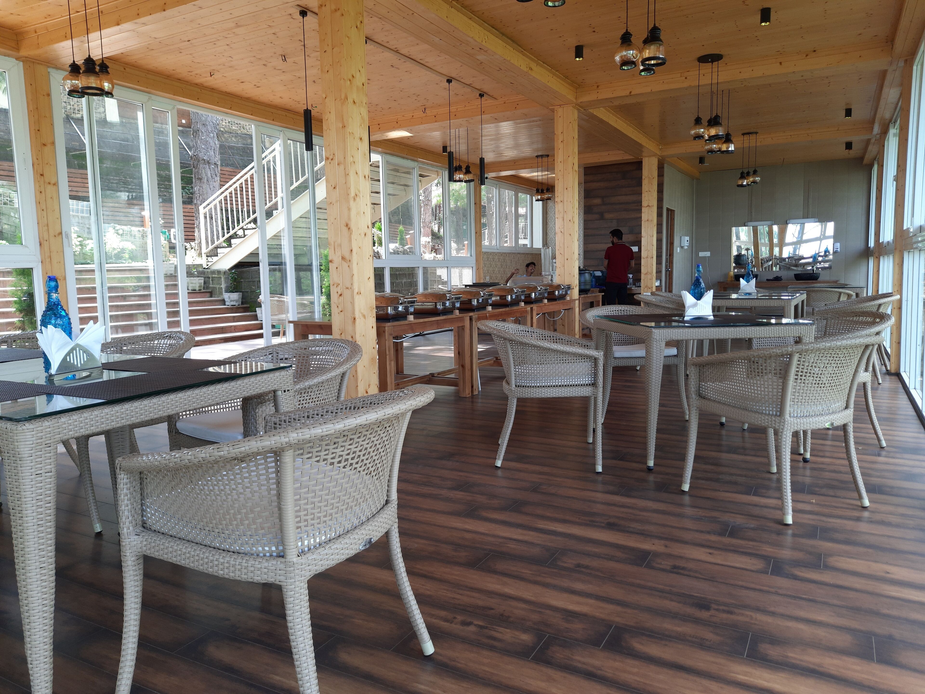 A spacious indoor area with wicker furniture, wooden flooring, and large windows.