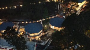 Un immeuble à plusieurs étages doté d’une cour intérieure, entouré d’arbres et comprenant plusieurs niveaux avec des terrasses extérieures.