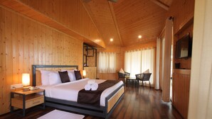 Une chambre à coucher aux murs lambrissés, comprenant un lit, des tables de chevet, une chaise et un téléviseur.