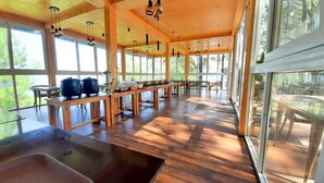 Un vaste espace dédié à la salle à manger, avec des tables et des chaises en bois, de grandes fenêtres et une vue sur l’extérieur.