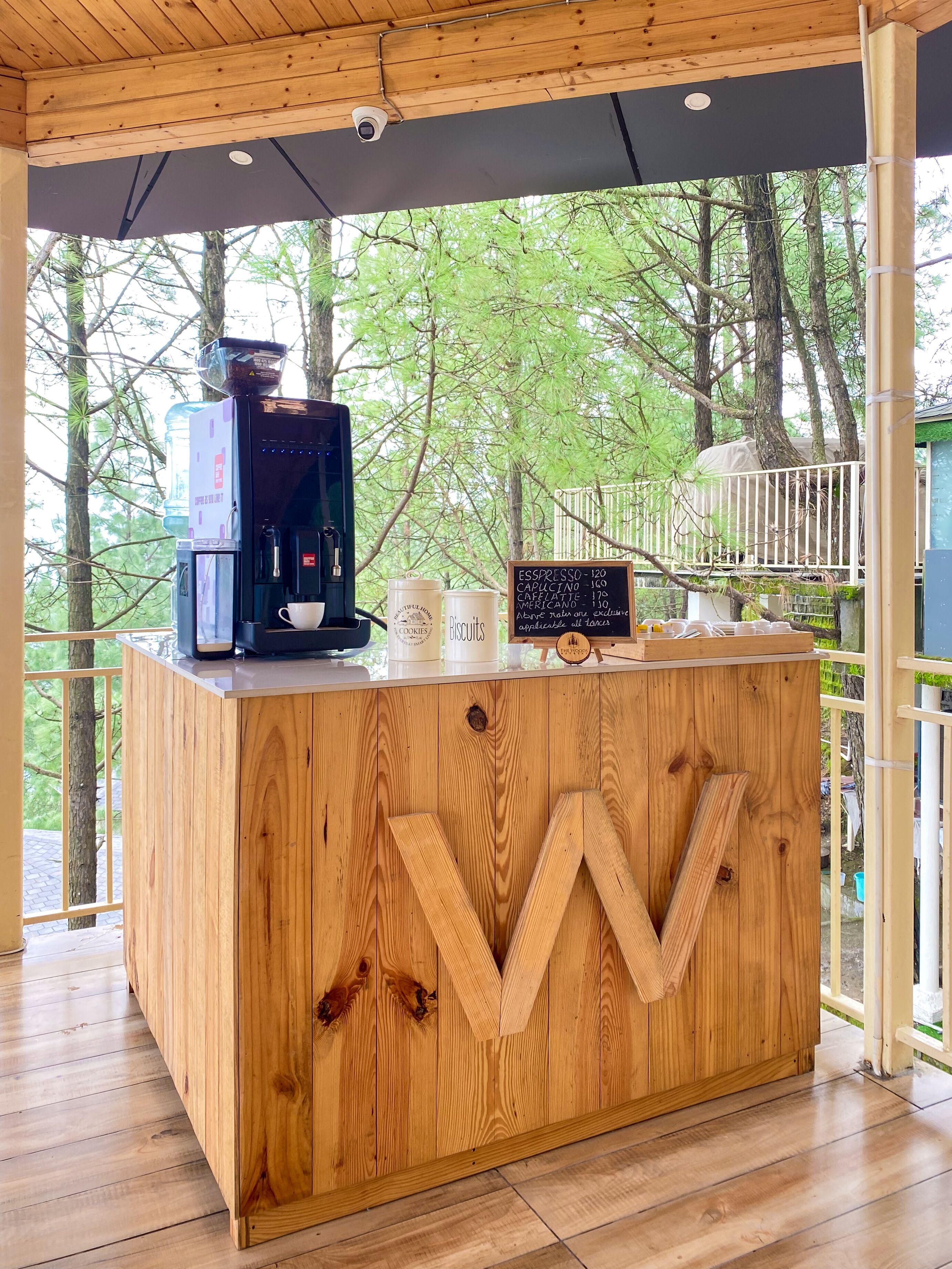 A wooden counter with a coffee machine, a menu board, and a cup.