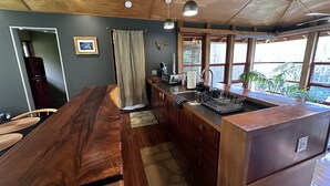A kitchen with a wooden countertop, a sink, and a window with a view of greenery.