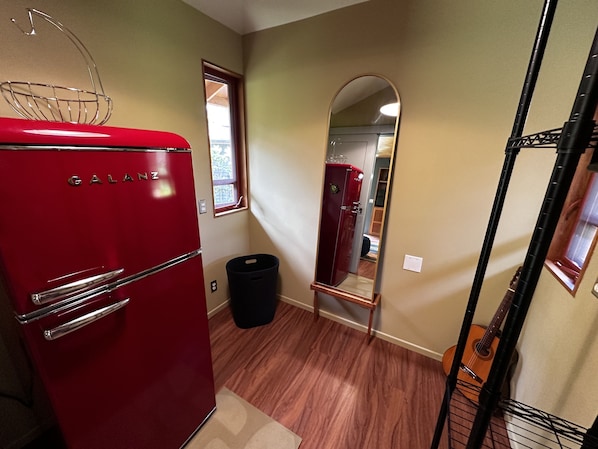 A compact kitchen with a red Galanz refrigerator, a black trash bin, and a wooden floor. - Tree Top Suite- Beautiful walk to Hanalei Bay (Princeville)
