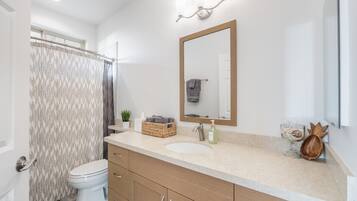 Ein modernes Badezimmer mit Toilette in Weiß, einem beige farbenen Waschbecken und einem Holzwaschtisch.