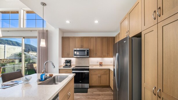 Una cocina moderna con armarios de madera, electrodomésticos de acero inoxidable y un amplio ventanal con vistas al exterior.