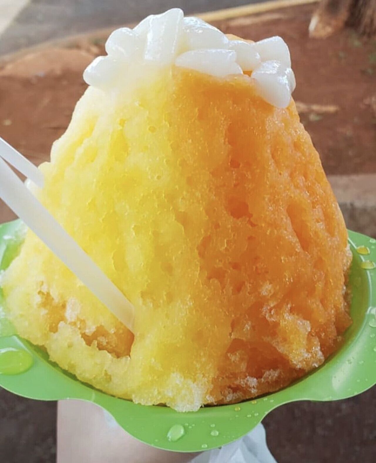 A dessert with a white topping, served on a green plate with a white straw.
