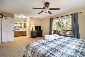 A bedroom with a bed, a ceiling fan, a TV, a dresser, and a window with curtains. - Classic Yosemite Cabin • Room for the Whole Family (Groveland)