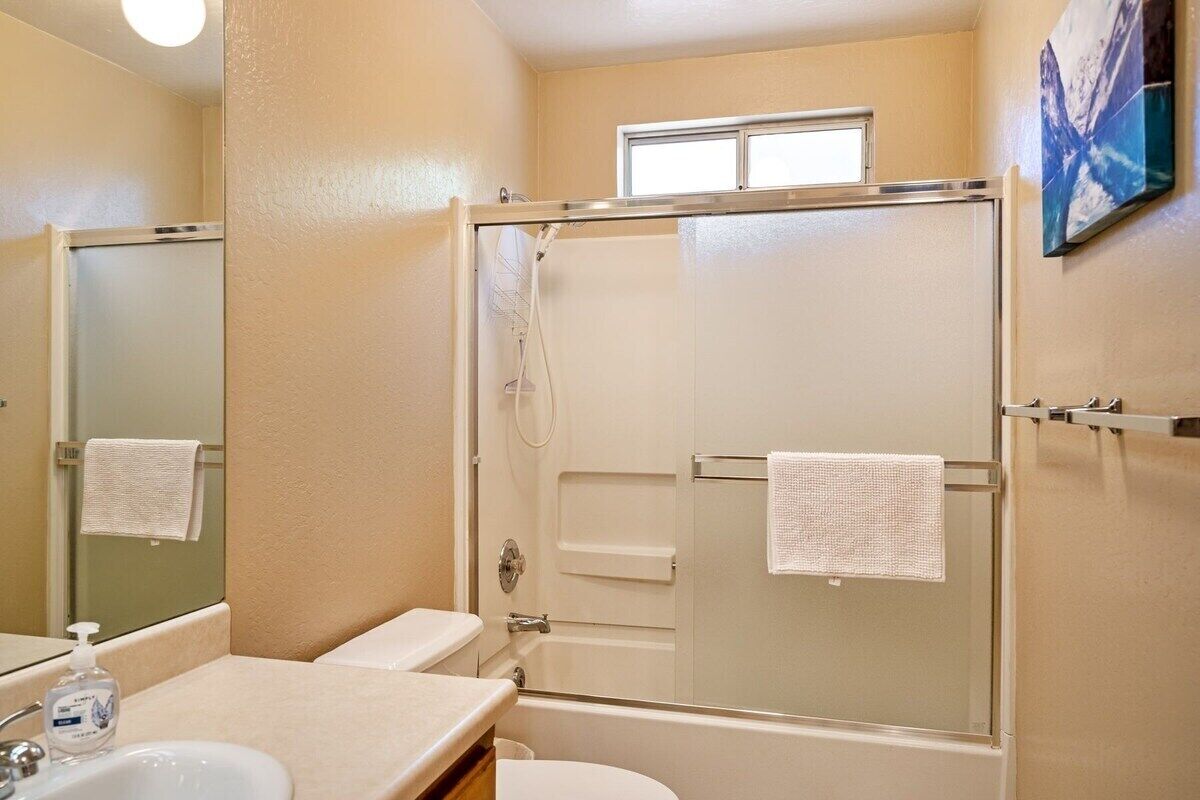 A bathroom with a glass-enclosed shower, a sink, and a toilet.